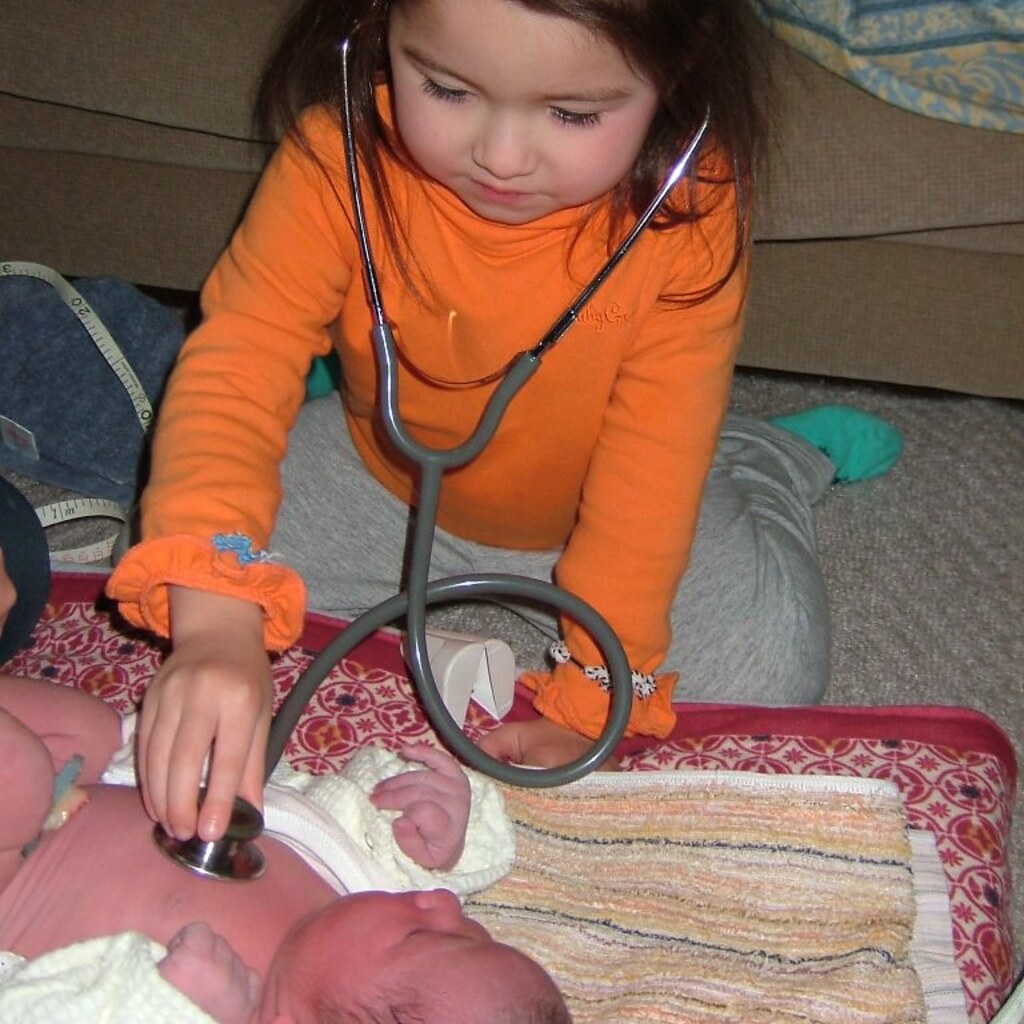 Photo of a little girl using a stethoscope on a baby