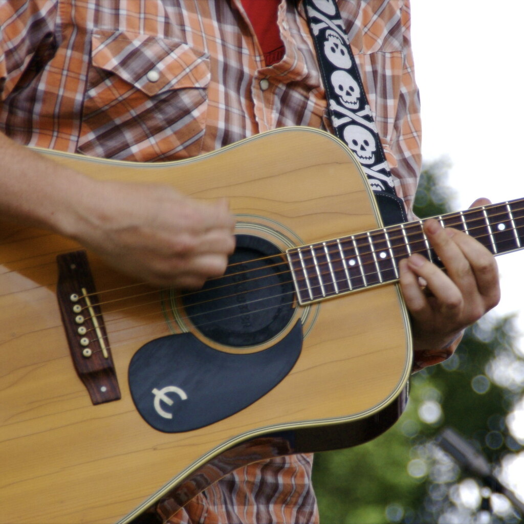 Photo of a man strumming a guitar.