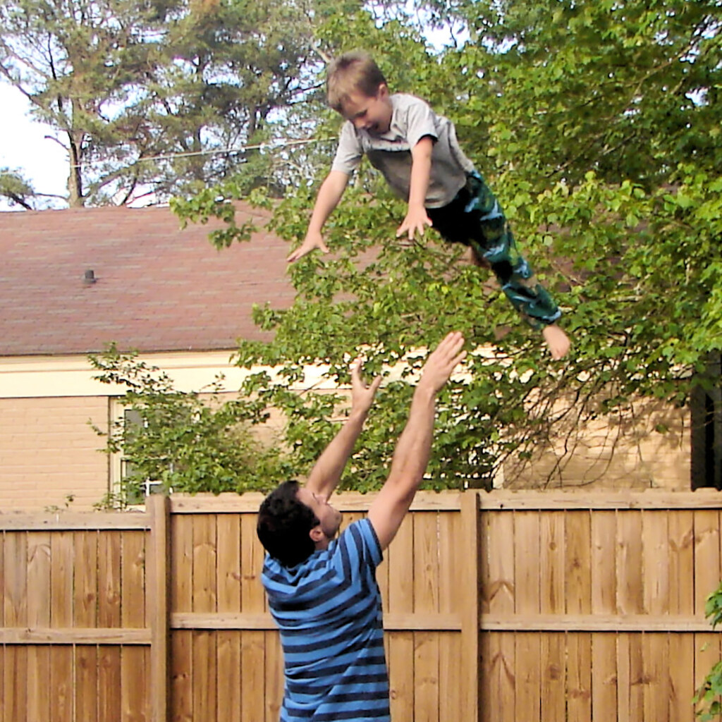 Photo of a man tossing a boy