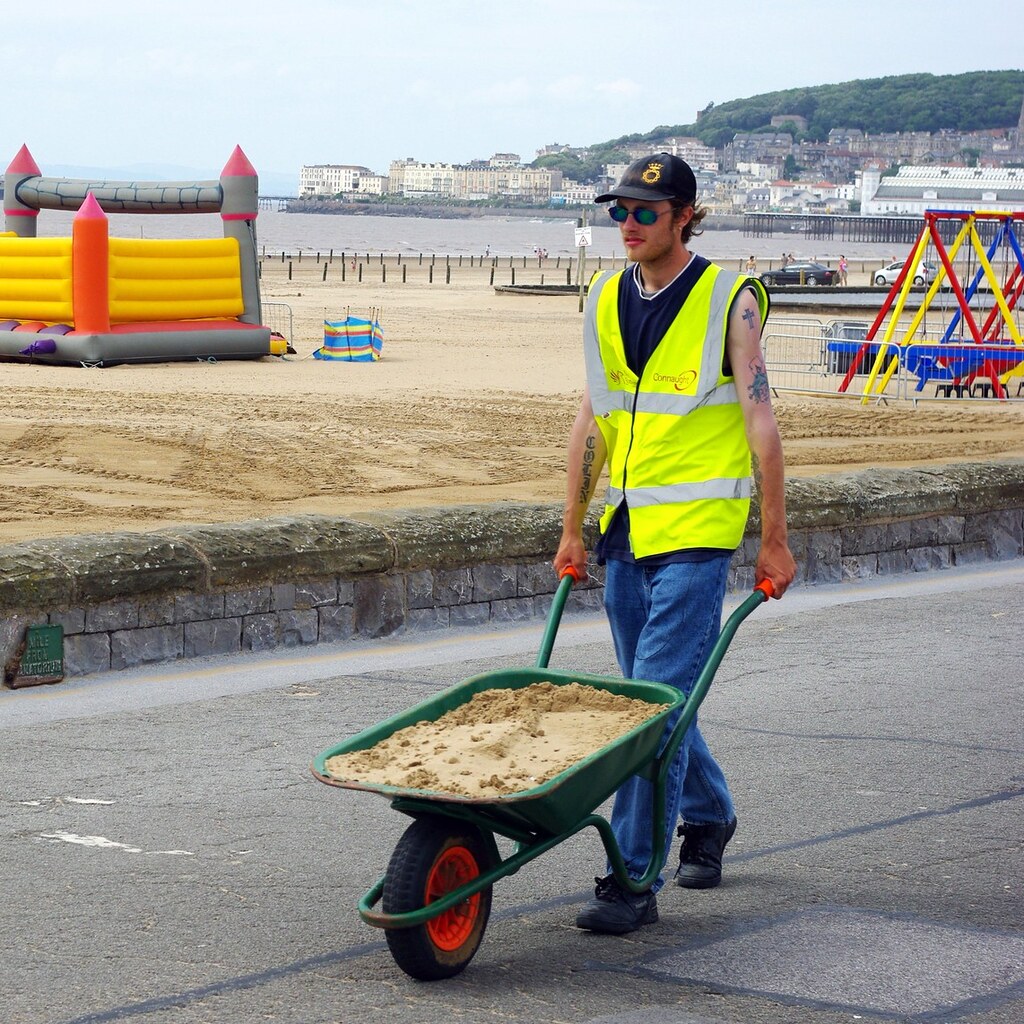Photo of a man pushing a wheelbarrow