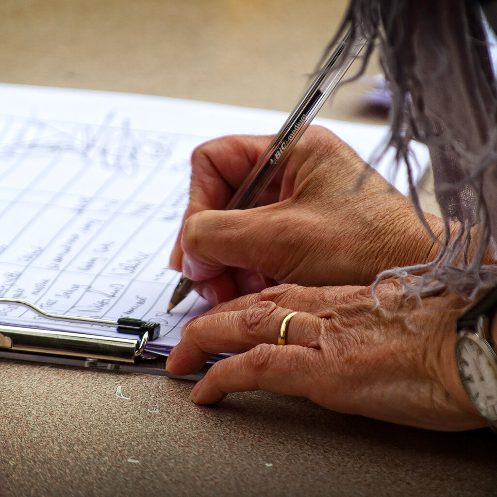 Photo of someone writing on a petition