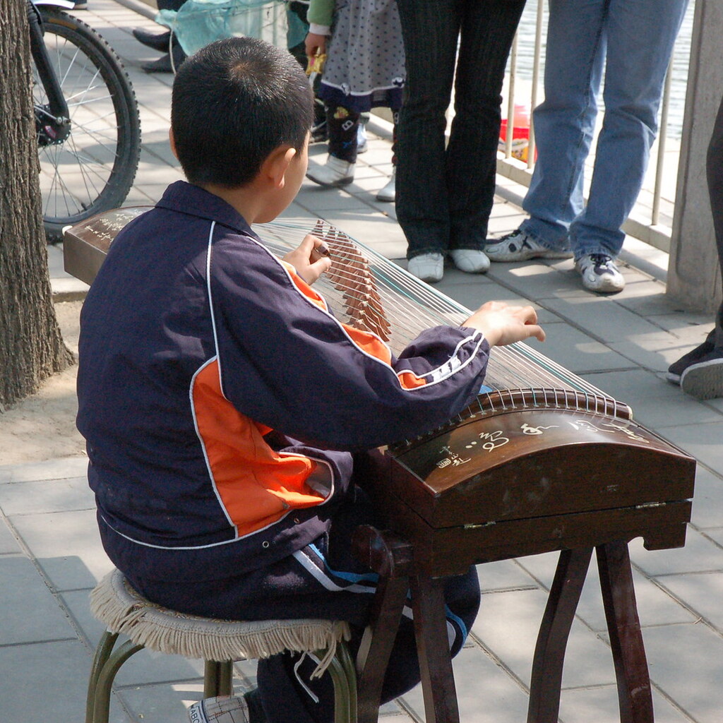 Photo of a boy playing a zither.